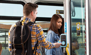 Two passengers boarding a Metro vehicle using a TAP card and reader.